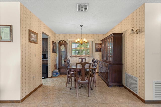 tiled dining space with a textured ceiling and an inviting chandelier