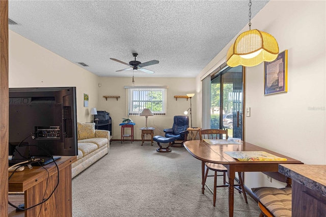 carpeted living room with ceiling fan and a textured ceiling