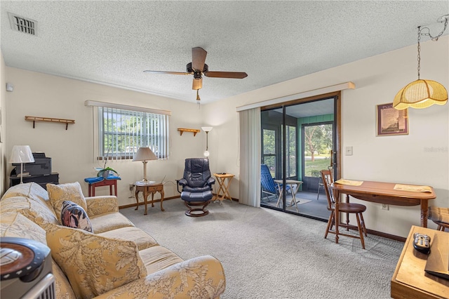 carpeted living room with ceiling fan, a textured ceiling, and a wealth of natural light