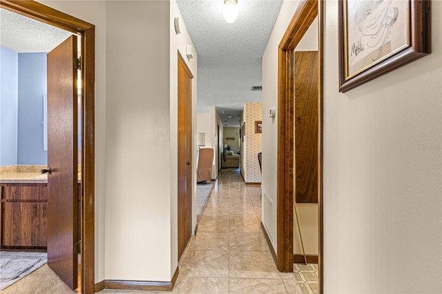 hallway featuring light tile patterned flooring and a textured ceiling