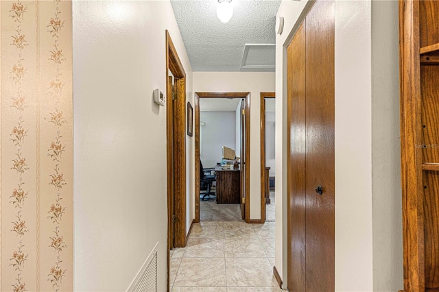 corridor featuring light tile patterned flooring and a textured ceiling