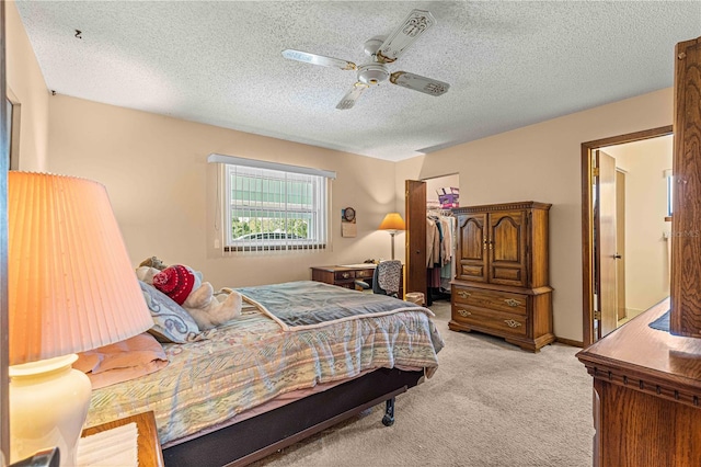 carpeted bedroom featuring ceiling fan and a textured ceiling