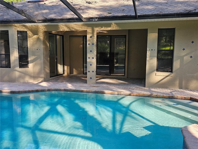 pool featuring glass enclosure and a patio