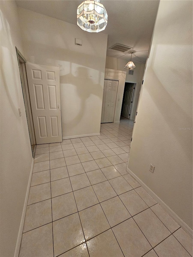 unfurnished room featuring light tile patterned floors and a chandelier