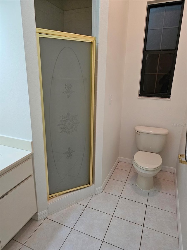 bathroom featuring toilet, vanity, a shower with shower door, and tile patterned flooring