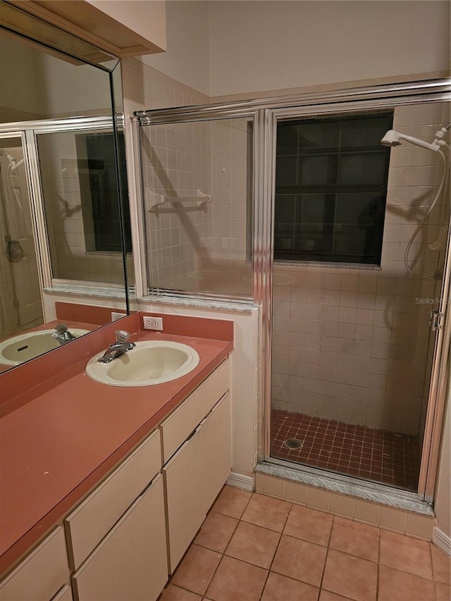 bathroom with a shower with shower door, vanity, and tile patterned floors