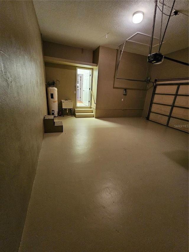 basement featuring water heater, sink, and a textured ceiling