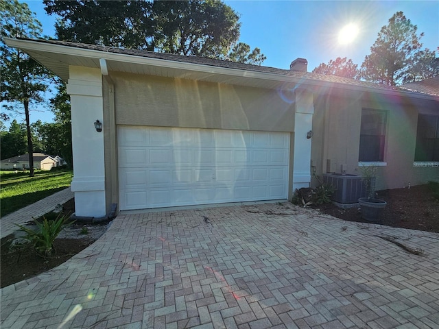 garage with decorative driveway and central AC