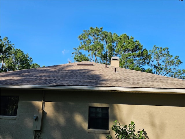 exterior space featuring stucco siding, a chimney, and roof with shingles