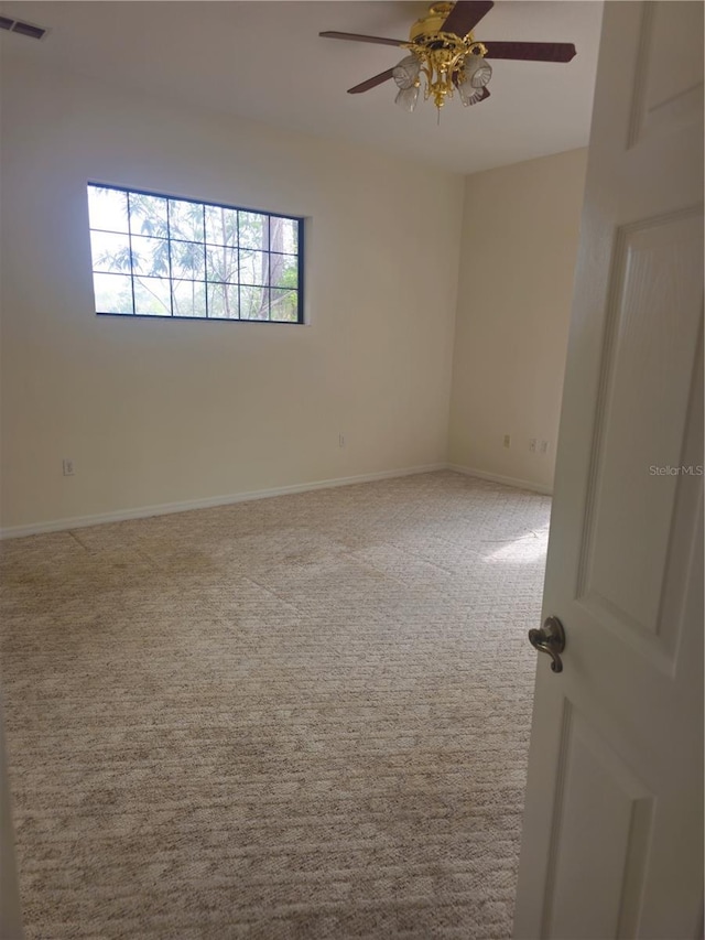 empty room featuring carpet floors, visible vents, ceiling fan, and baseboards