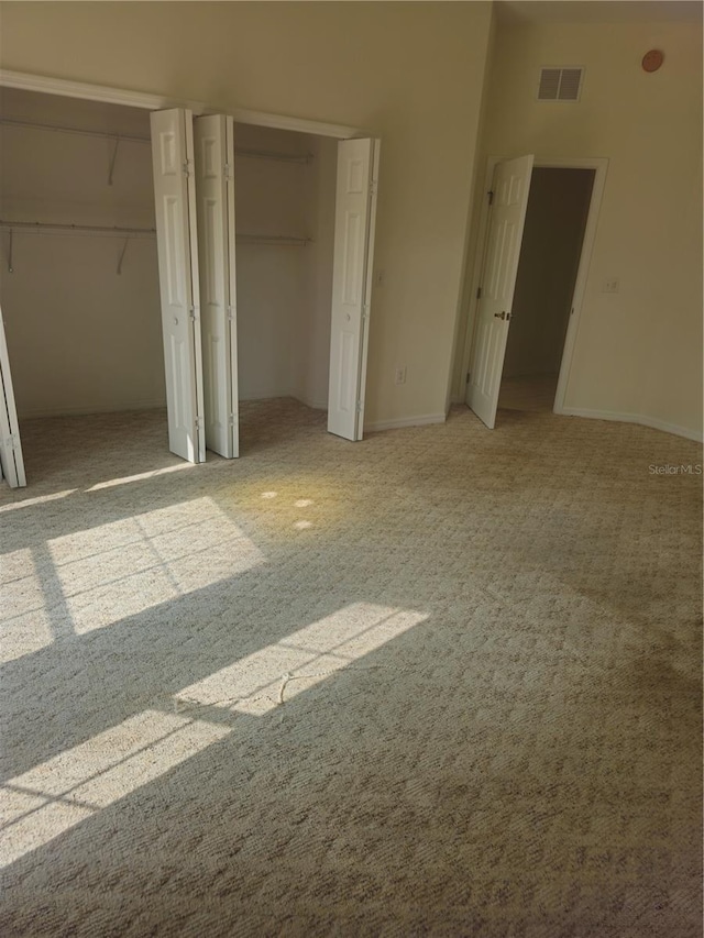 unfurnished bedroom with visible vents, light carpet, baseboards, and two closets