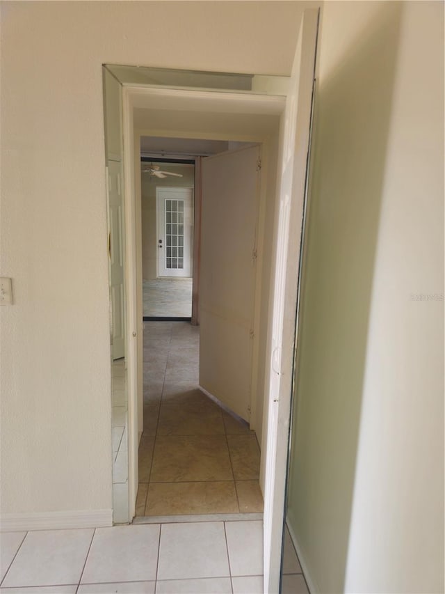 hall featuring light tile patterned floors and baseboards