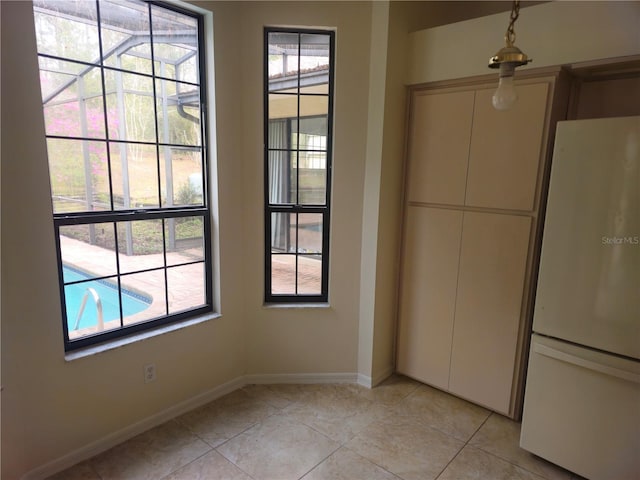 unfurnished dining area with light tile patterned floors and baseboards