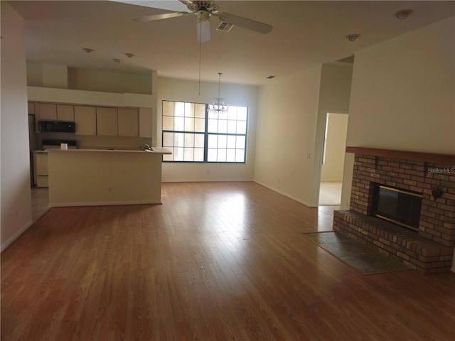 unfurnished living room featuring baseboards, visible vents, a ceiling fan, light wood-style flooring, and a fireplace