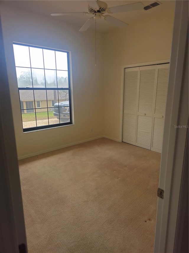 unfurnished bedroom featuring light carpet, baseboards, visible vents, and a closet