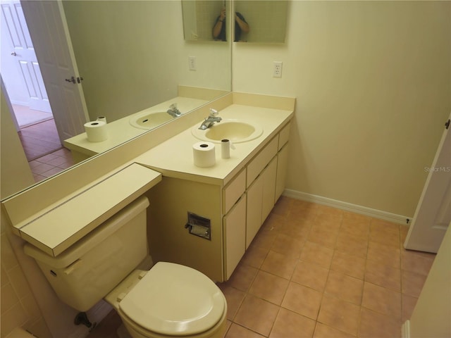 half bath with toilet, baseboards, vanity, and tile patterned floors