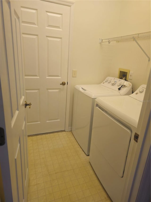 clothes washing area featuring laundry area, light floors, and washing machine and clothes dryer