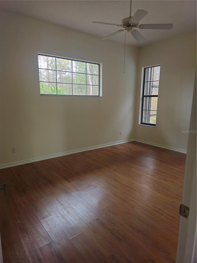 unfurnished room with baseboards, dark wood-type flooring, and a wealth of natural light