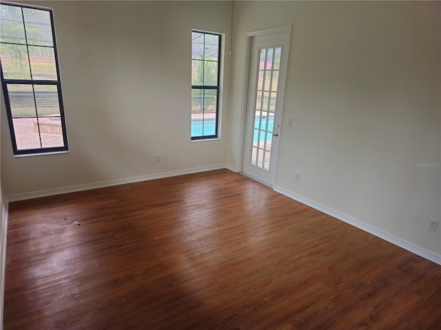 unfurnished room with dark wood-style floors and baseboards