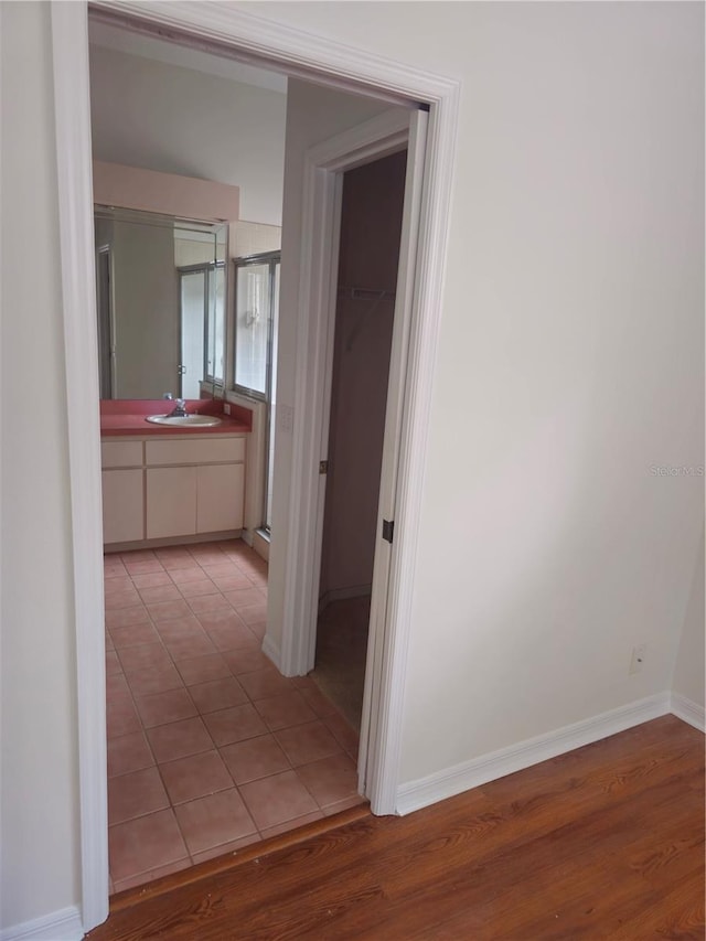 hall featuring a sink, light wood-style flooring, and baseboards