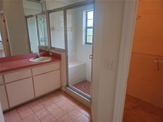 full bath featuring a shower stall, a spacious closet, tile patterned flooring, and vanity