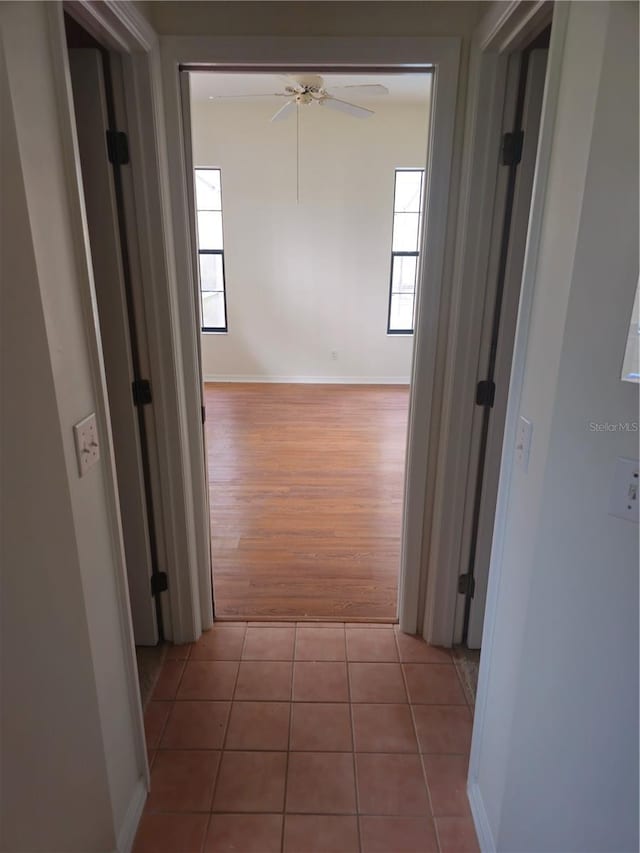 hall with light tile patterned flooring and baseboards