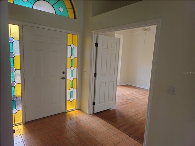 tiled foyer with a ceiling fan and baseboards