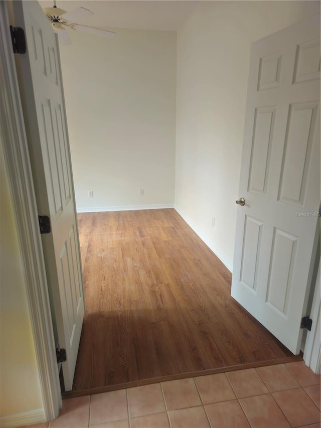 empty room with baseboards, ceiling fan, and light wood-style floors