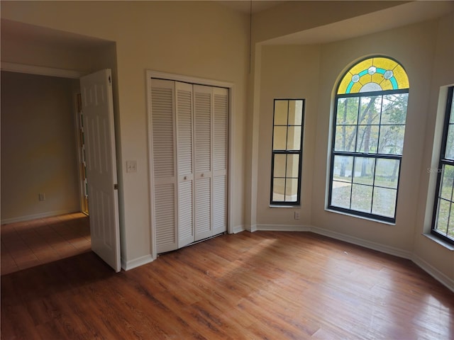 unfurnished bedroom featuring a closet, baseboards, and wood finished floors