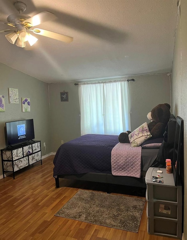 bedroom featuring ceiling fan, hardwood / wood-style flooring, and a textured ceiling