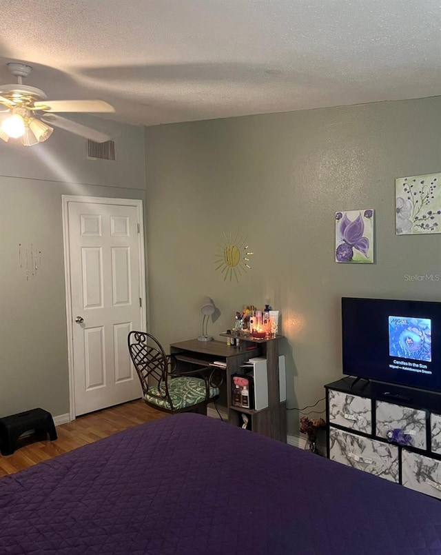 bedroom featuring ceiling fan, a textured ceiling, and hardwood / wood-style floors