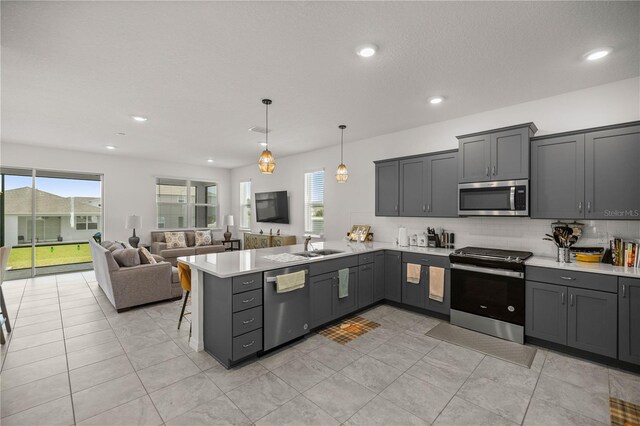 kitchen featuring decorative backsplash, appliances with stainless steel finishes, light tile patterned floors, decorative light fixtures, and kitchen peninsula