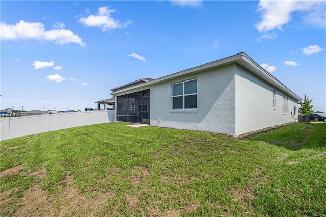 back of house featuring a sunroom, central AC unit, and a lawn