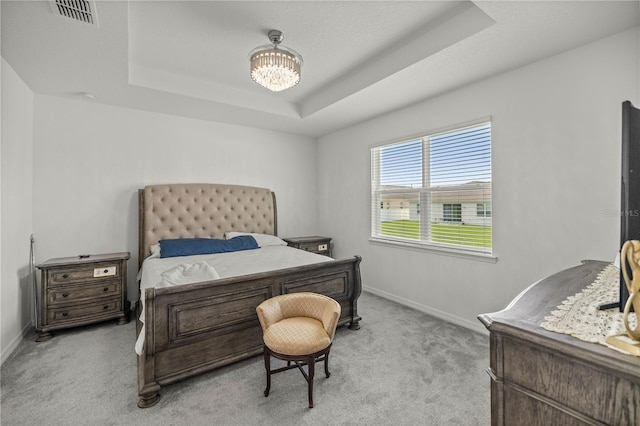 carpeted bedroom featuring a raised ceiling and a notable chandelier