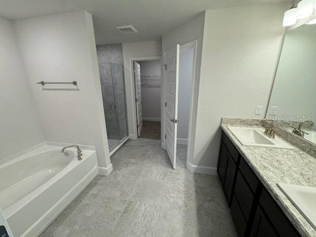 bathroom with double vanity, a spacious closet, a stall shower, a sink, and a bath