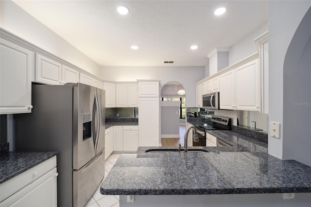 kitchen featuring a textured ceiling, stainless steel appliances, kitchen peninsula, and white cabinets