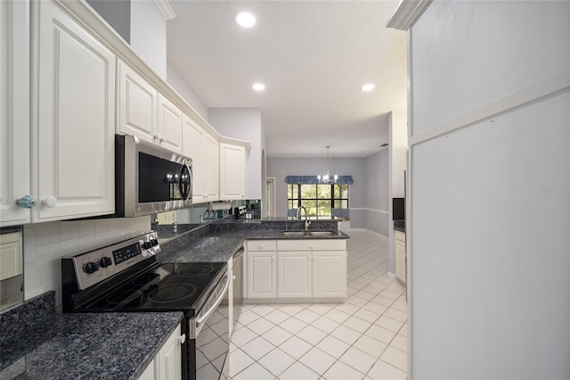 kitchen with appliances with stainless steel finishes, a chandelier, white cabinetry, sink, and light tile patterned flooring