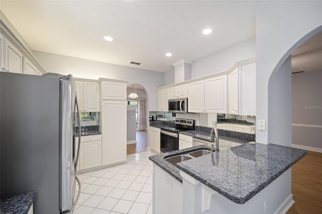 kitchen featuring light wood-type flooring, white cabinetry, kitchen peninsula, sink, and appliances with stainless steel finishes