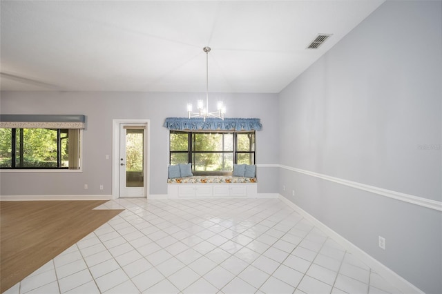 spare room featuring light wood-type flooring, a wealth of natural light, and a chandelier