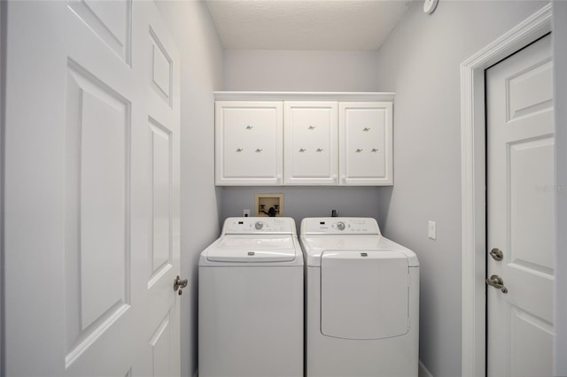 laundry room featuring a textured ceiling, cabinets, and washer and dryer