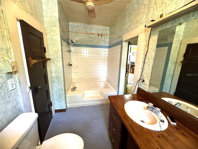 full bathroom featuring ceiling fan, vanity, tiled shower / bath combo, and toilet