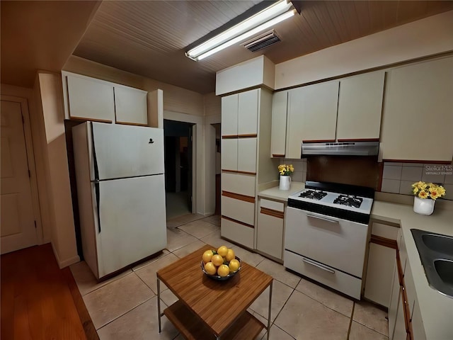 kitchen with decorative backsplash, white appliances, white cabinetry, and light tile patterned floors