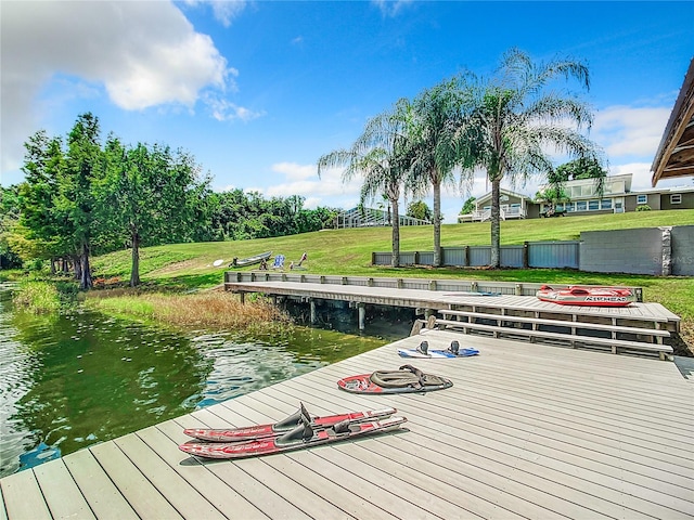 view of dock with a water view and a yard