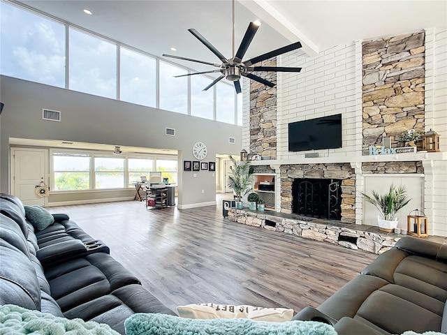 living room with beamed ceiling, a fireplace, hardwood / wood-style floors, high vaulted ceiling, and ceiling fan