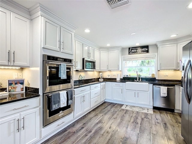 kitchen featuring light wood-type flooring, appliances with stainless steel finishes, sink, and white cabinets