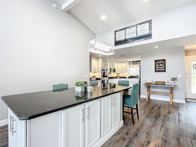 kitchen featuring a kitchen breakfast bar, white cabinets, high vaulted ceiling, hardwood / wood-style flooring, and dark stone counters