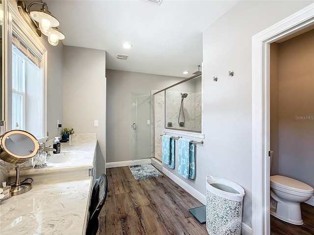 bathroom with vanity, toilet, hardwood / wood-style floors, and a shower with door