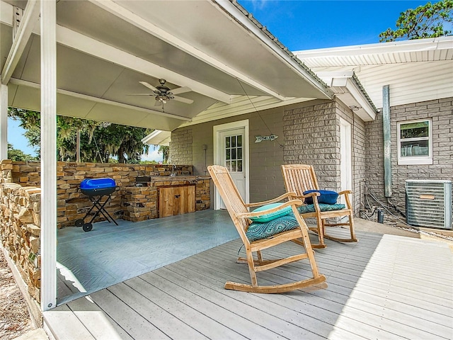 wooden terrace with area for grilling, exterior kitchen, ceiling fan, and central AC unit