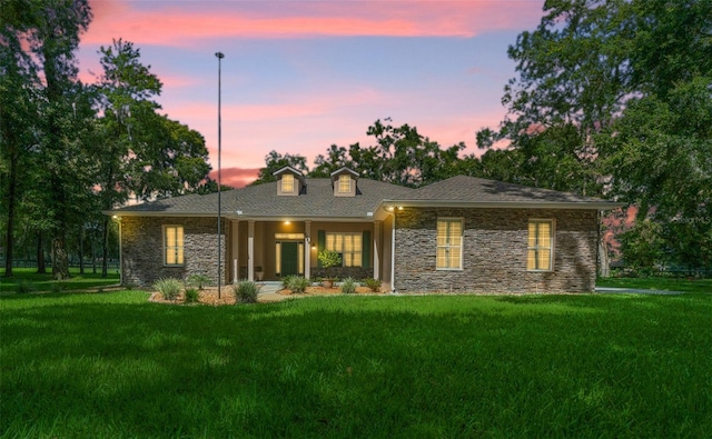 back house at dusk featuring a lawn