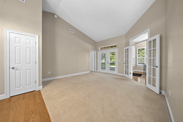 spare room with light carpet, high vaulted ceiling, and french doors